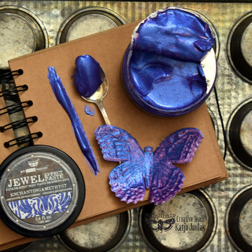 Blue craft supplies on a notebook and tin background.