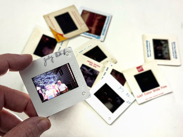 Hand holding a slide with other slides on a white surface.