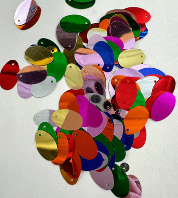 Colorful oval-shaped sequins scattered on a white surface.