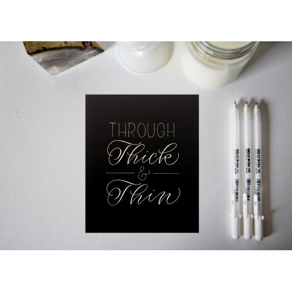 Black card with Through Thick & Thin and white pens.