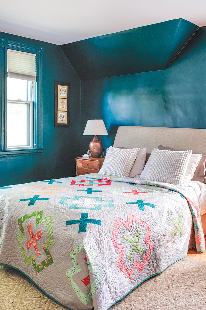 Bedroom with bed and colorful quilt.