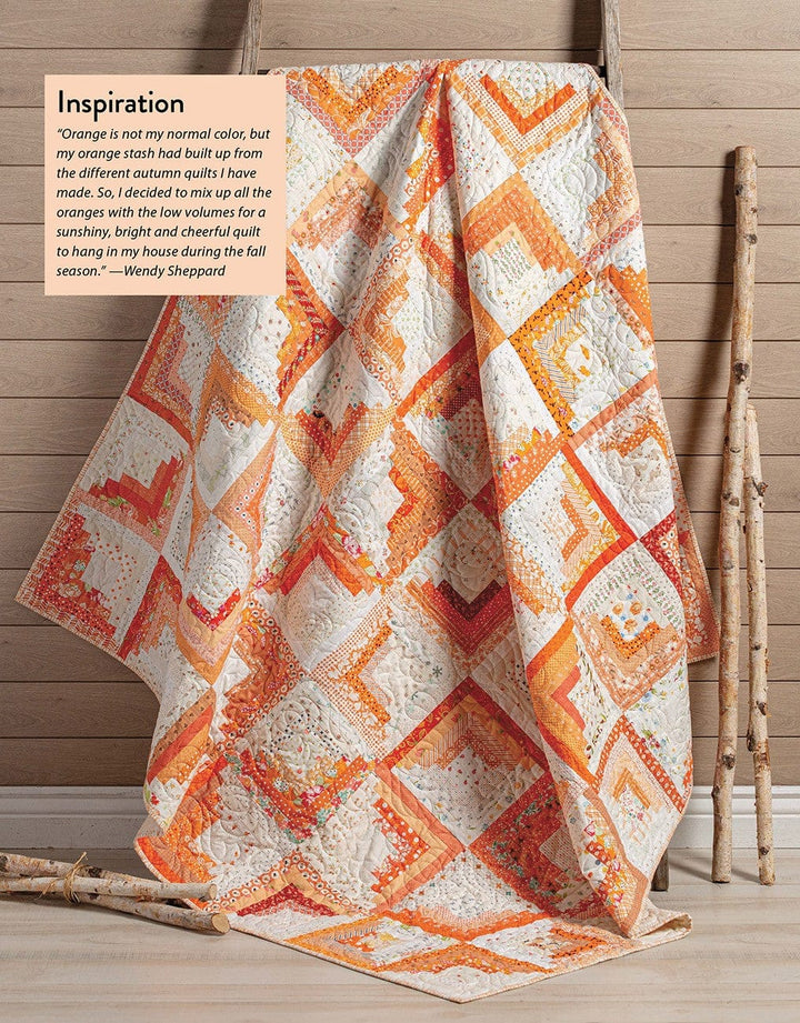 Orange and white quilt draped on a ladder.