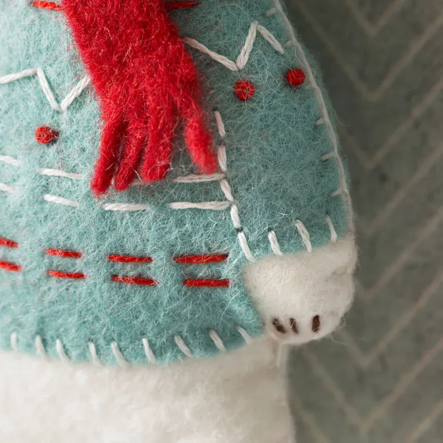 Close-up of a blue felt ornament with red details and white stitching.