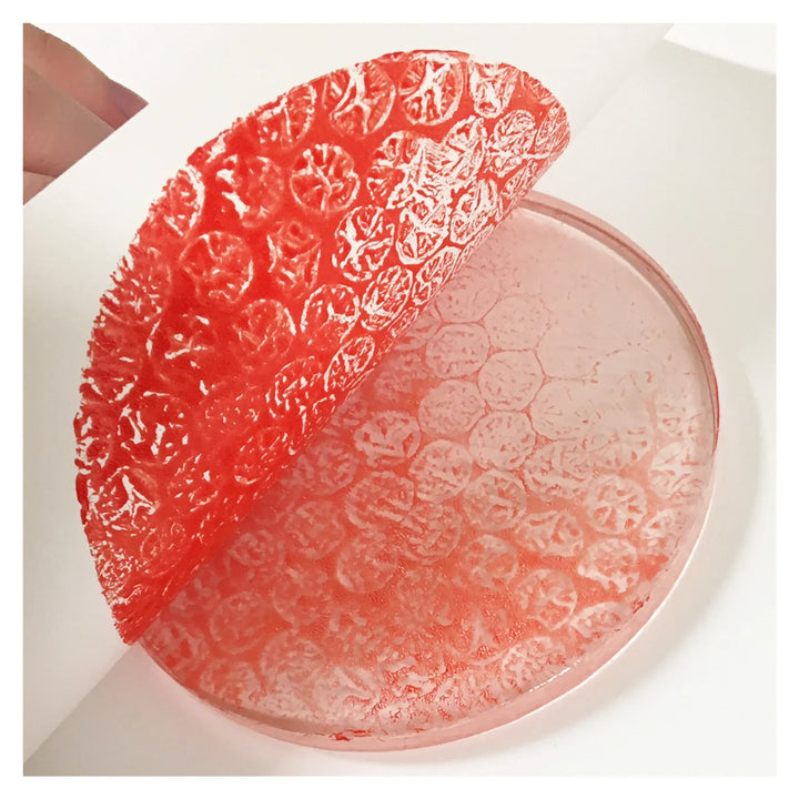 Red bubble wrap peeled from clear circular surface