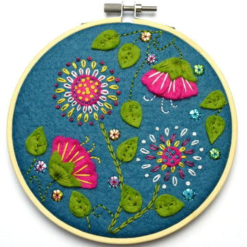 Embroidery hoop with pink and yellow flowers and green leaves.