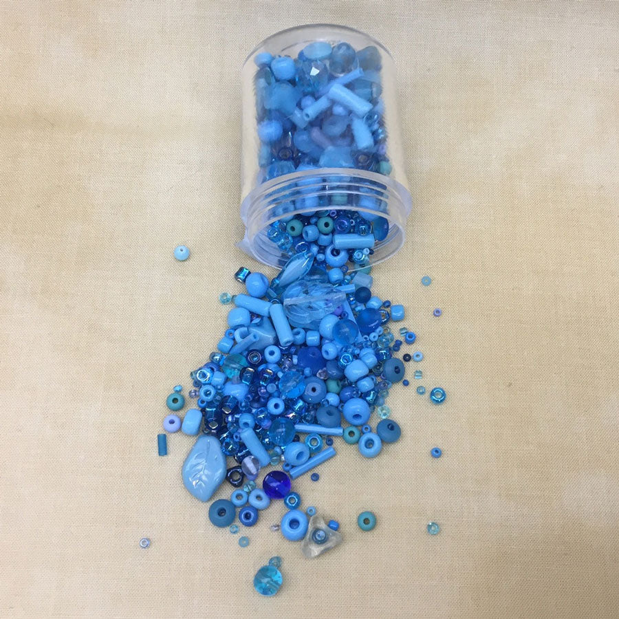 Blue beads spilling from a clear jar.