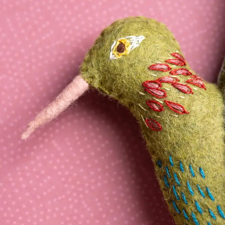 Felt hummingbird with pink beak and red/blue embroidery.