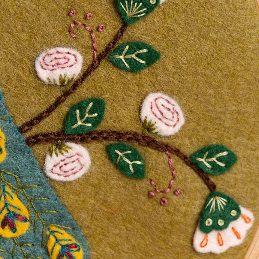 Embroidered floral branch on tan felt.