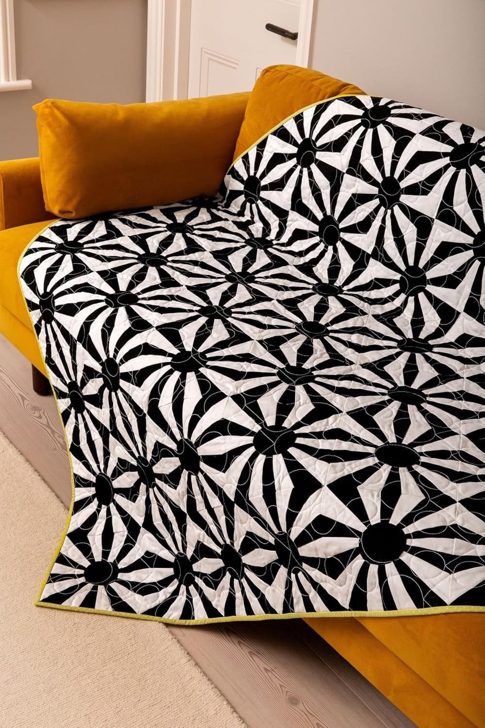 Black & white floral quilt on a yellow couch (DC15903_2)