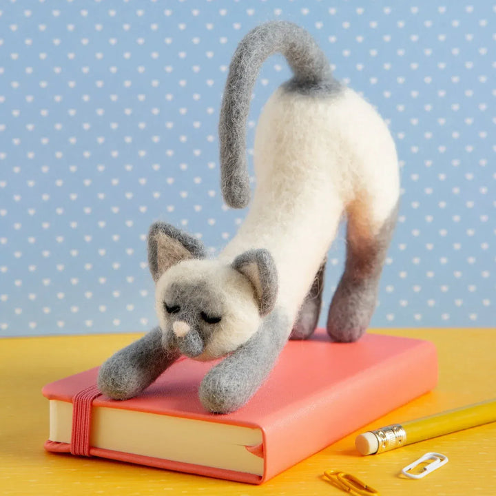 Needle felted stretching cat on book