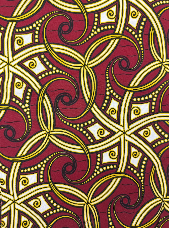 Red and yellow patterned fabric with swirls and geometric shapes.