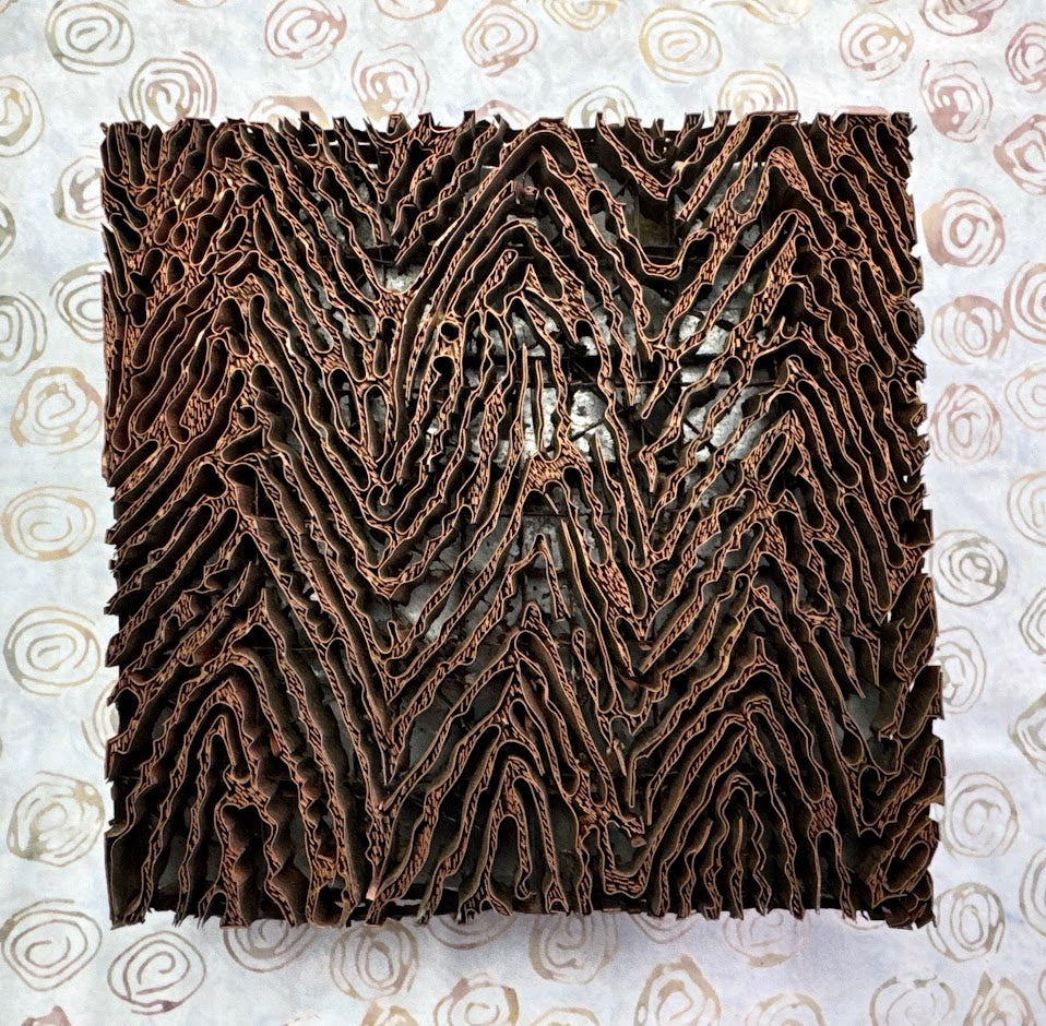 Copper Tjap textured square on a patterned background, like wood grain