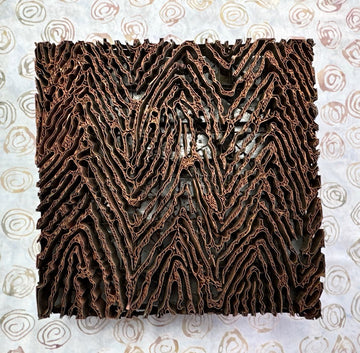 Copper Tjap textured square on a patterned background, like wood grain