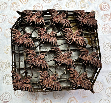 Bronze bird figurines on a metal grid against a patterned background