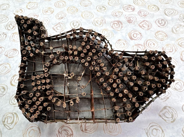 Decorative wall art shaped like a fish made from metal on a patterned background