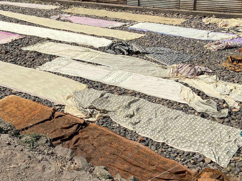 Fabric drying on a gravel surface.