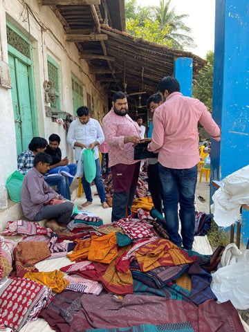 People sorting through textiles outside a building.