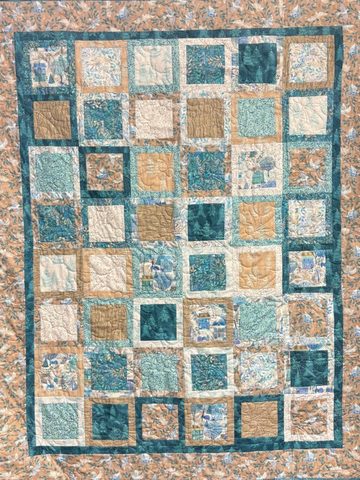 Peaceful quilt with squares of teal, tan, and floral patterns.