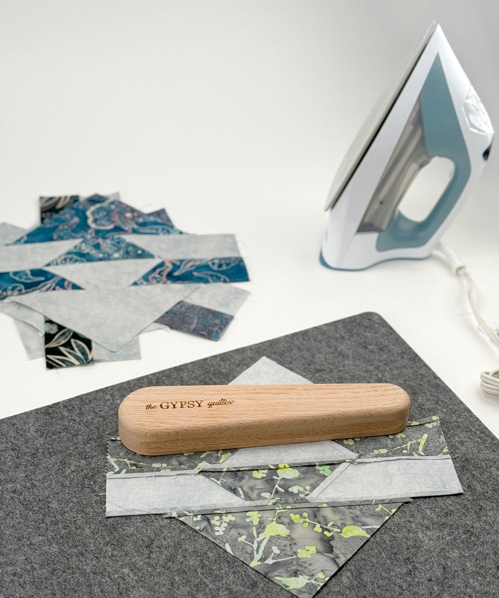 Quilting process with iron, fabric, and wooden press.