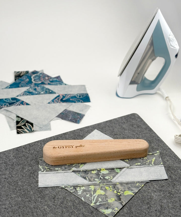 Quilting process with iron, fabric, and wooden press.