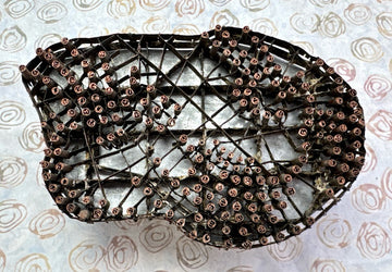 Decorative metal mesh with copper rivets on a textured beige background