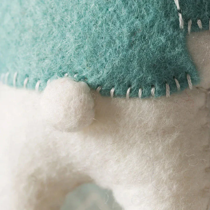 Close-up of felt object with teal and white fabric and white stitching.