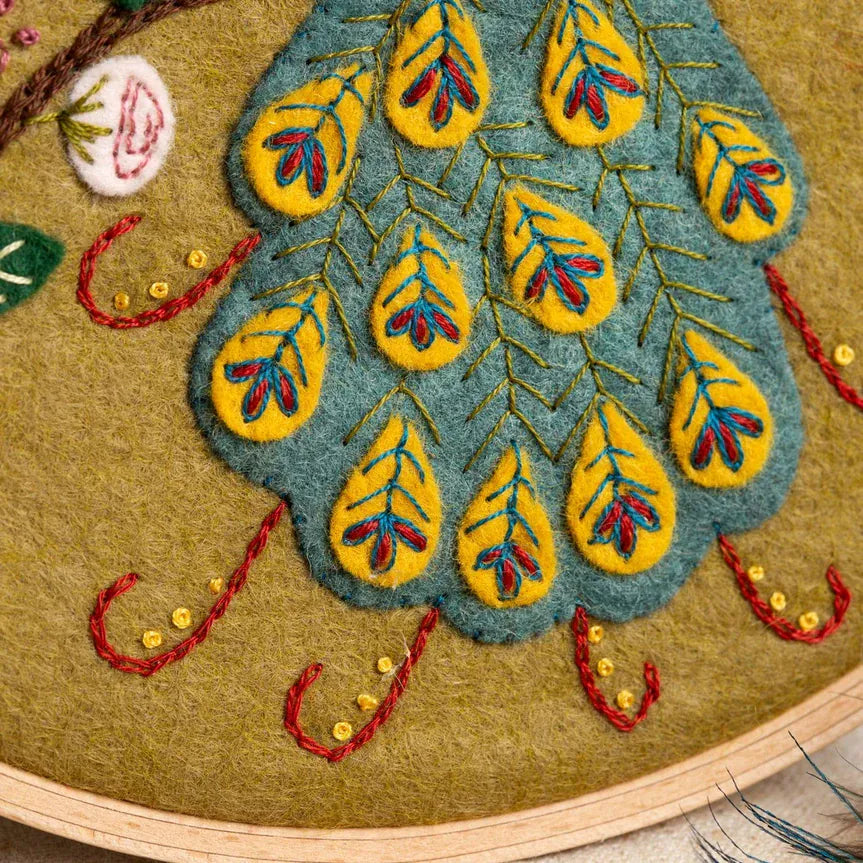 Embroidered peacock tail on fabric in a hoop.
